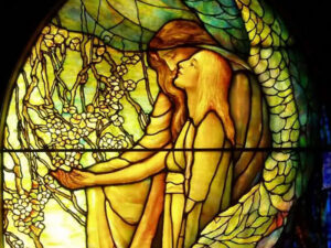Stained glass artwork depicting a serene moment between two figures surrounded by floral motifs and vibrant colors.